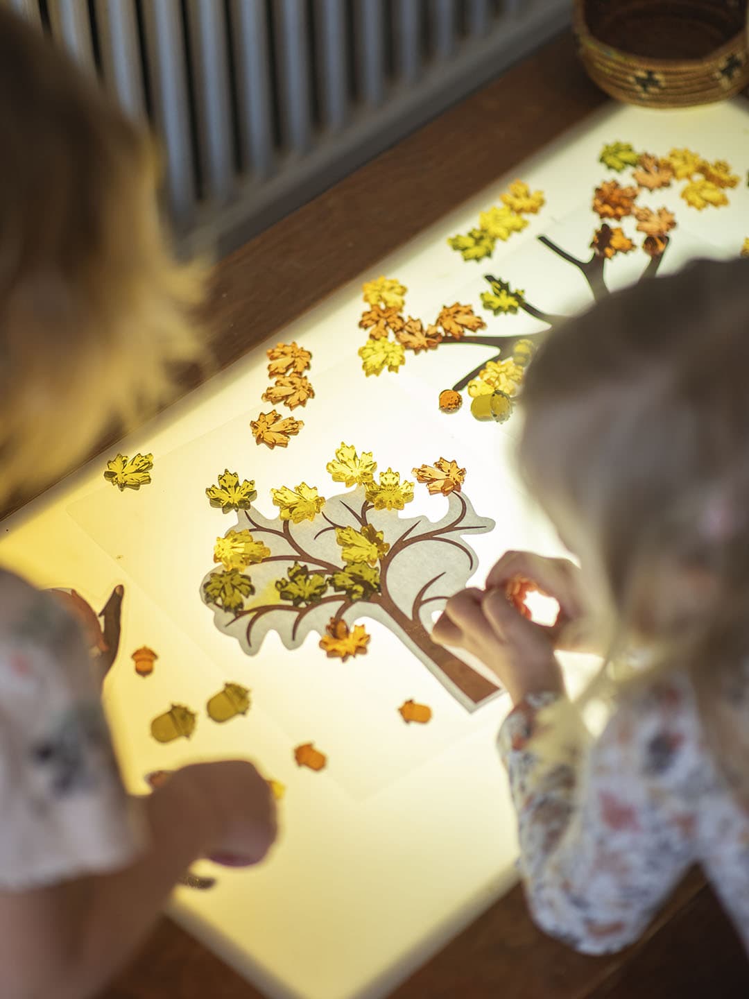 Children arranging autumn leaves on a glowing light table at Cornerstone Daycare.